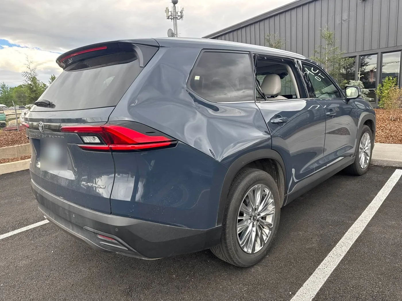 Blue Toyota Grand Highlander Platinum with a large dent in the rear quarter panel behind the rear door